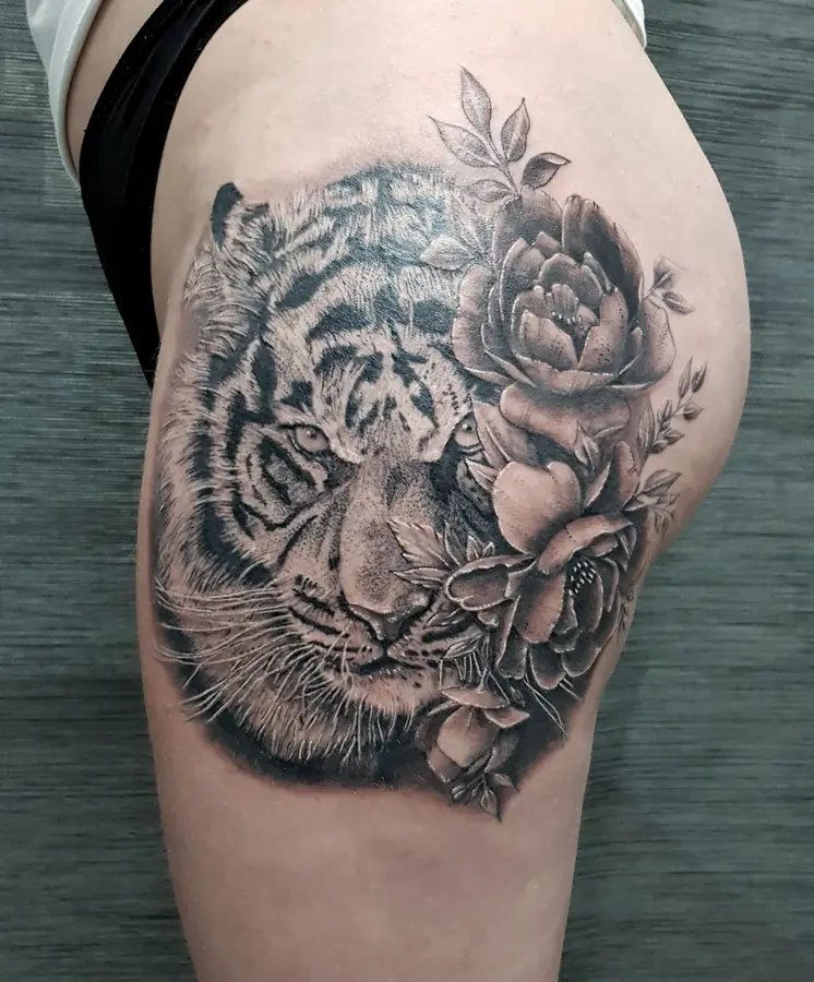 Realistisches Tattoo am Oberschenkel: Tigerkopf mit Pfingstrosen