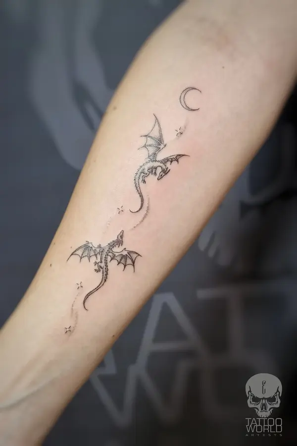 Fine-Line-Tattoo am Unterarm: zwei kleine Drachen, Mond und Sterne